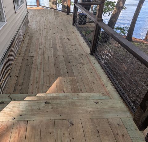 New deck boards and wire-panel railing on a lakefront deck